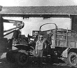 George standing in front of the truck that was hit by a German grenade.